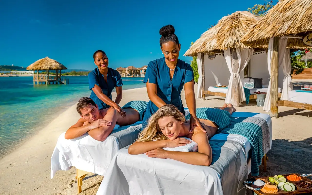2 Black women giving beach massage to a white couple in Jamaica